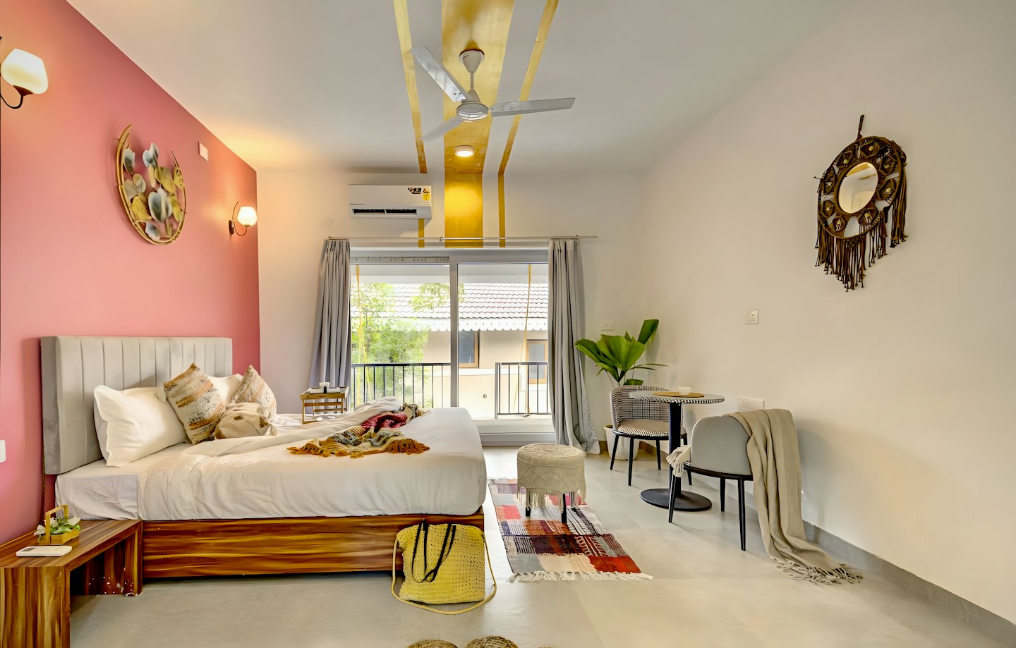 Moderne hotelsuite slaapkamer met roze accentmuur en balkon.