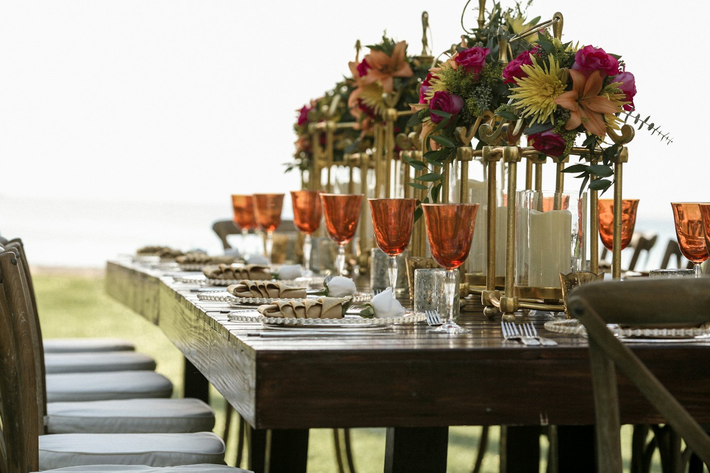 Buiten eettafel gedekt met rozen en lantaarns voor een feest.