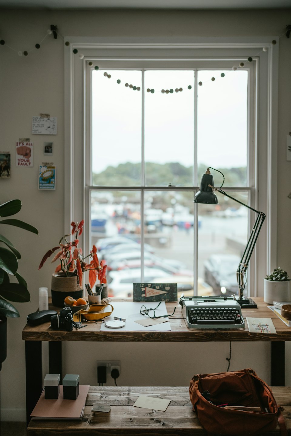 Rustiek bureau met typemachine en planten bij een groot raam.